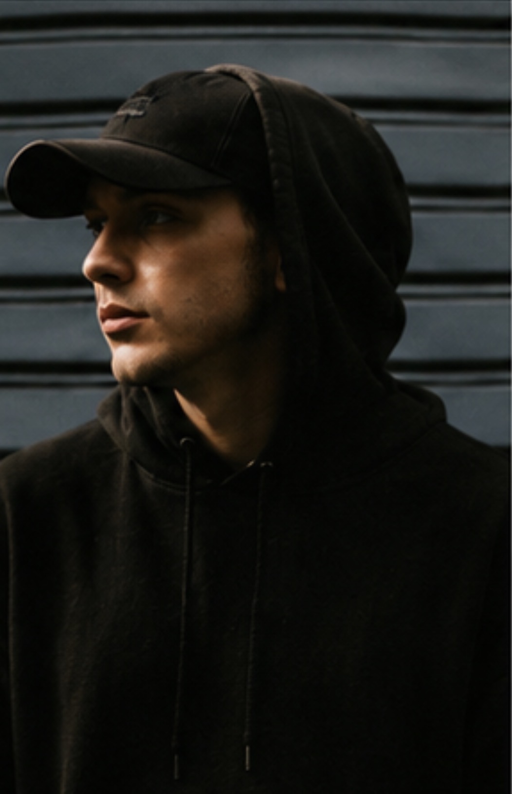 Blackwork — hooded figure in a black cap, face turned away