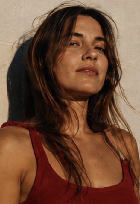 Velour — sunlit portrait in a red vest against a pale wall